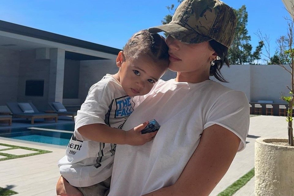 Foto colorida de Kylie Jenner e o filho caçula, Aire Webster. A empresária está de boné e camisa branca - Metrópoles
