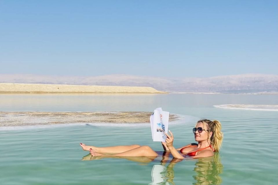 foto colorida de Eliana deitada no mar morto lendo revista - metrópoles