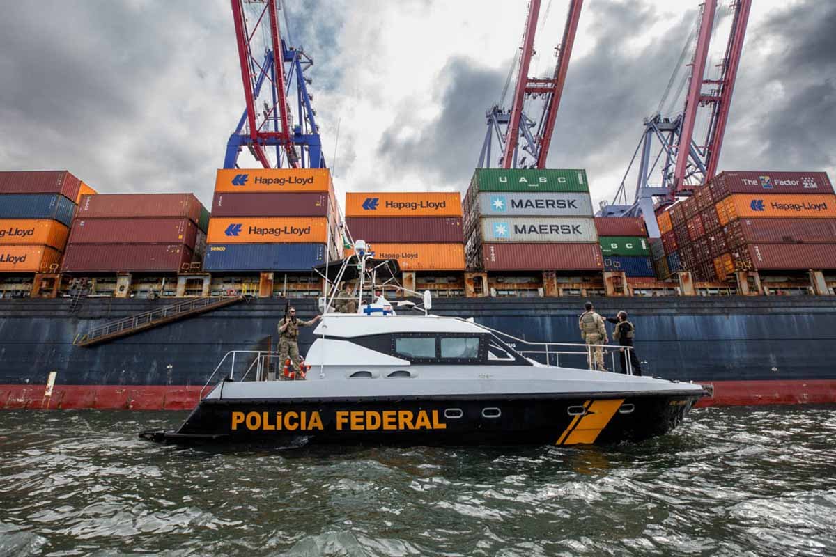 imagem colorida de Barco da Polícia Federal em frente a um navio no porto do rio de janeiro