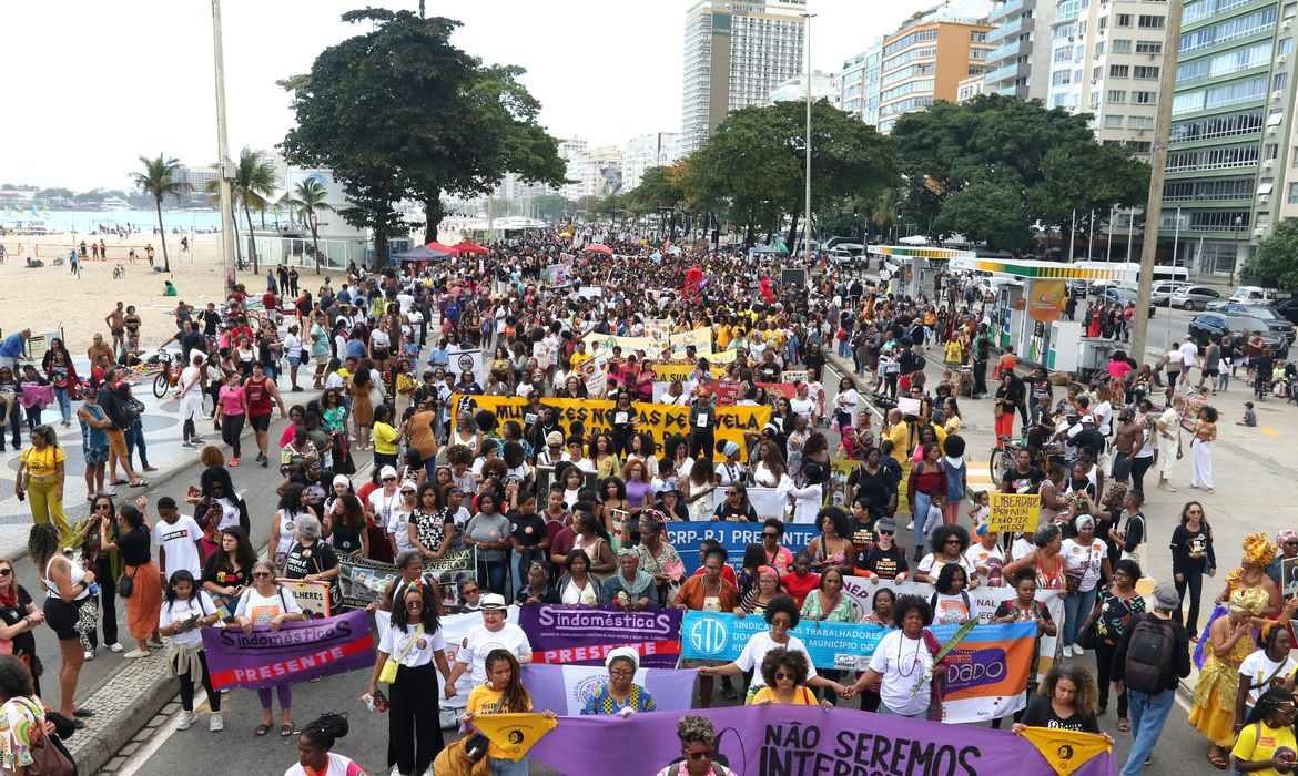 Foto mostra multidão de mulheres com faixas ocupando Copacabana