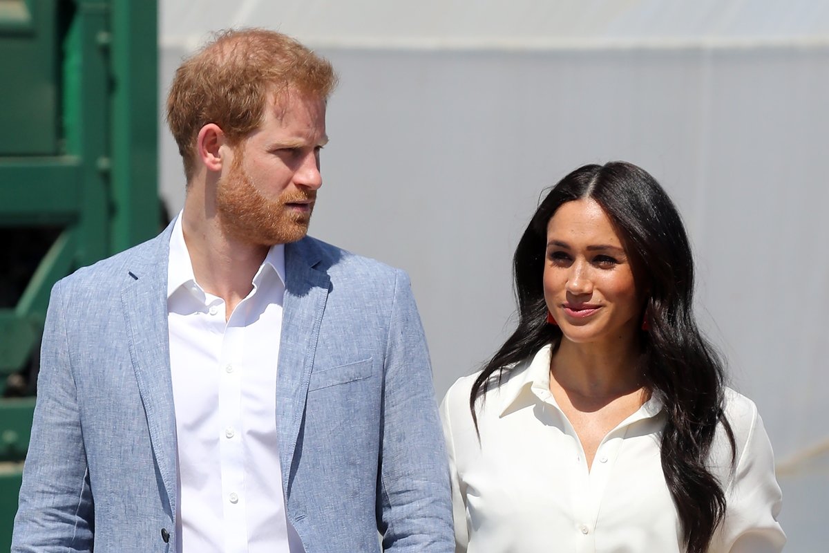 Color image.  The photo shows the couple Harry and Meghan.  He is a white man with red hair and wearing a light blue suit.  She is a black woman with long straight hair - Metropolis