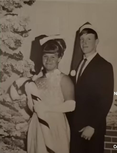 Foto antiga em tons sépia mostracasal com roupas natalinas olhando a câmera