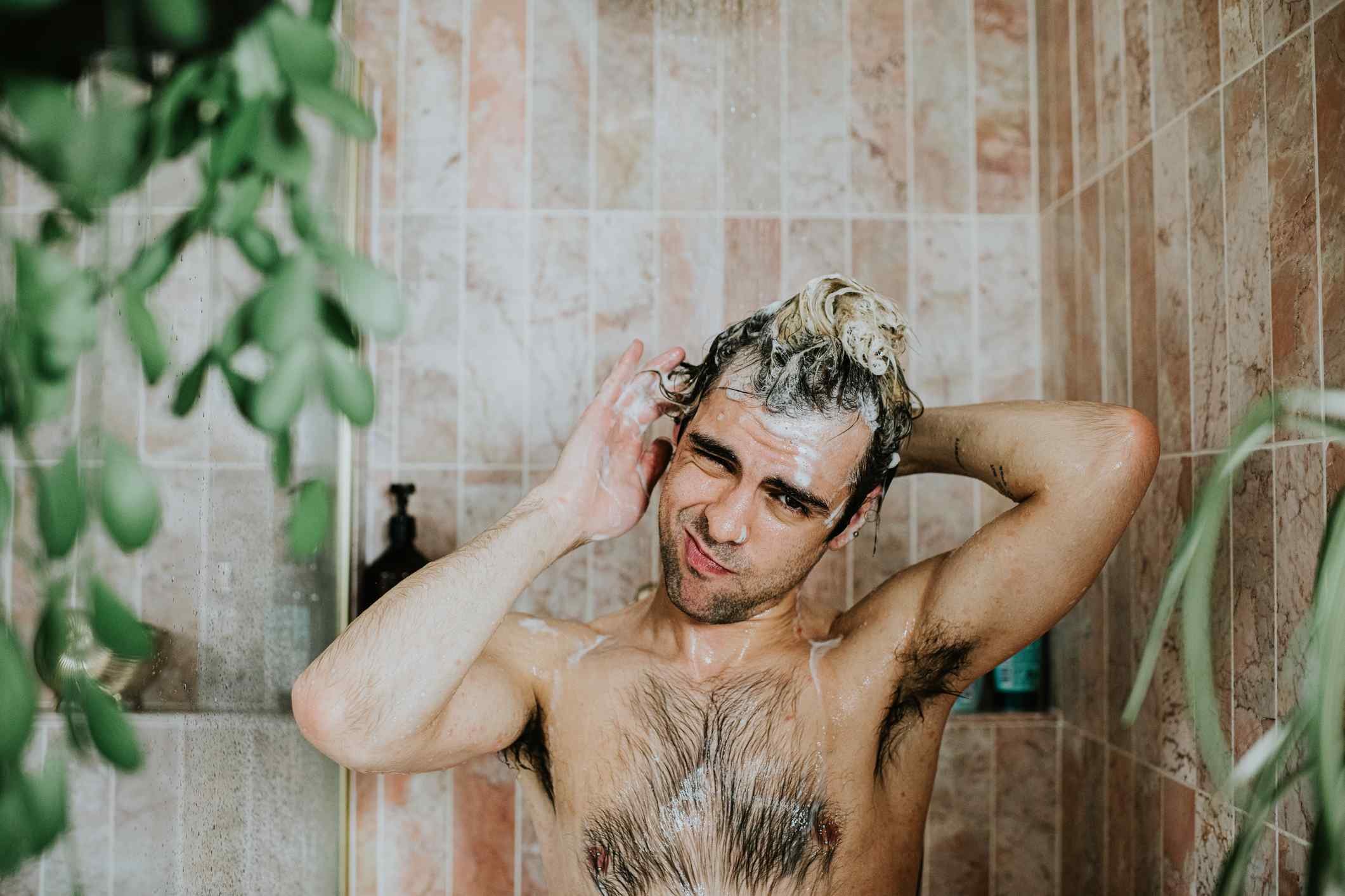 Foto mostra homem jovem tomando banho e coçando o ouvido - Metrópoles