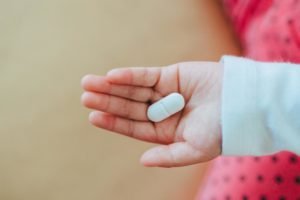 mão de criança com remédio em comprimido opioides - Metrópoles
