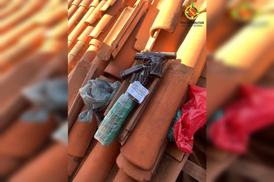 Arma, simulacro de arma e sacolas com objetos em cima de um telhado