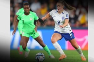 Imagem corodida de jogadoras da Inglaterra e Nigéria em campo pela Copa do Mundo Feminina de Futebol