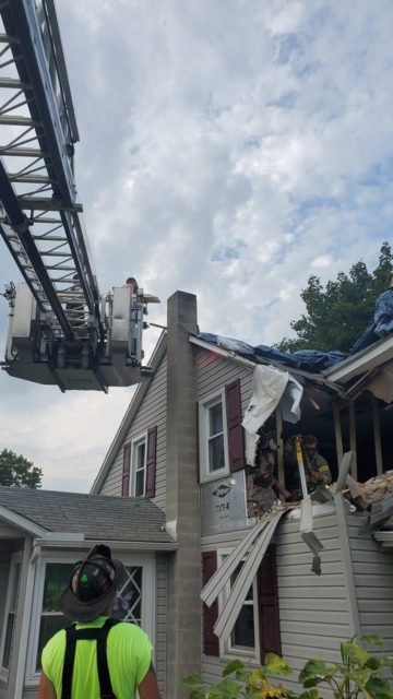 Imagem colorida de equipe dos bombeiros durante resgate de motorista do carro que parou no segundo andar de uma casa nos EUA - Metrópoles