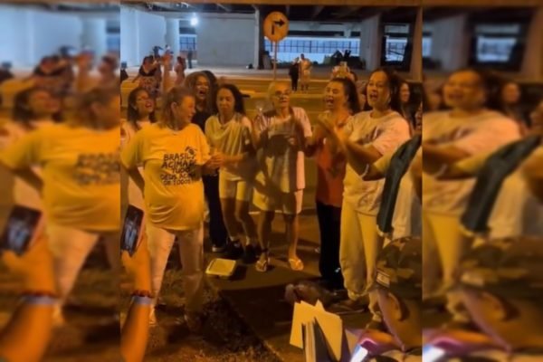 Grupo de mulheres em uniforme branco comemora soltura da prisão feminina