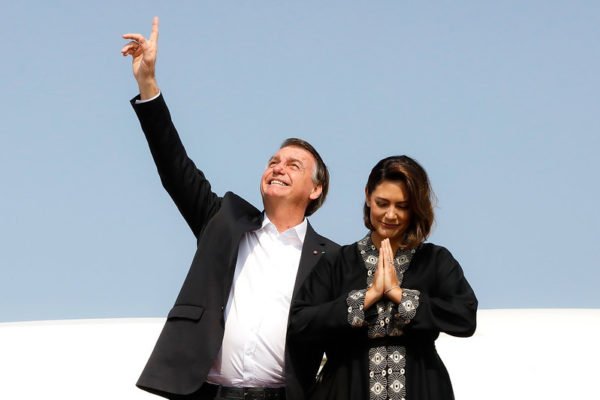 O então presidente, Jair Bolsonaro, aponta para o céu, enquanto a então primeira-dama, Michelle Bolsonaro, faz gesto de oração