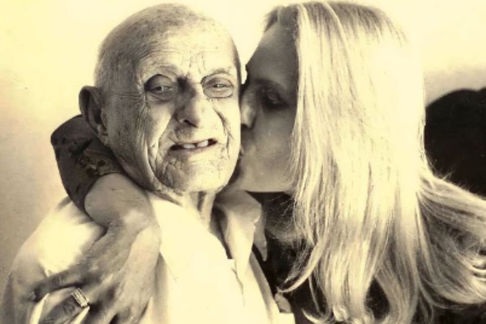 Na imagem, um homem idoso e uma mulher beijando-o - Metrópoles