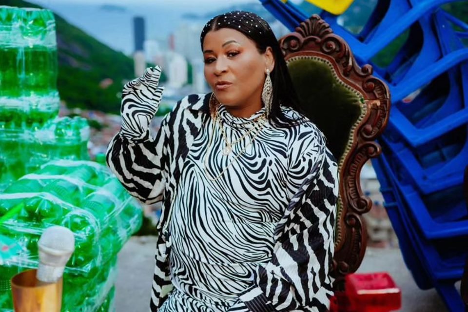 Foto colorida de MC Katia. Ela é negra, tem o cabelo preto e está com uma roupa preta e branca - Metrópoles