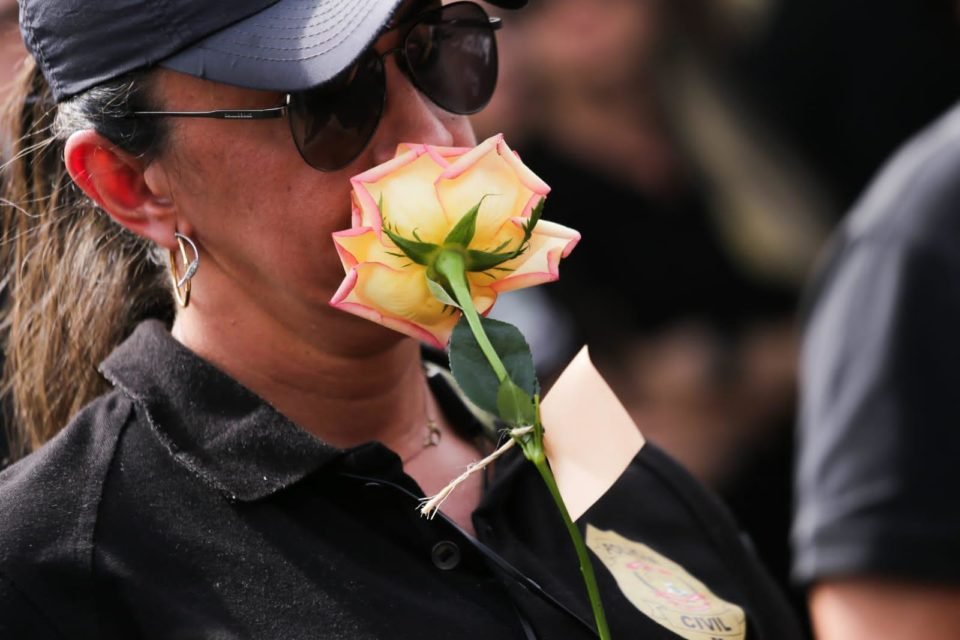 Mulher de luto cheira flor. Ela veste preto, boné e