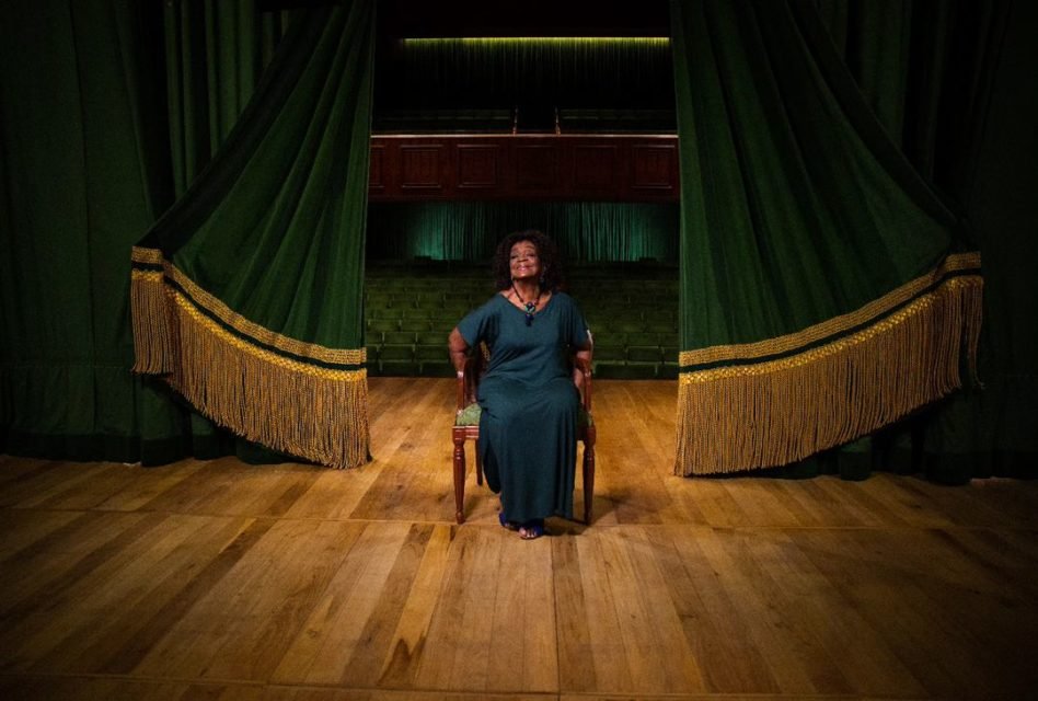 Foto colorida de Léa Garcia. Ela é negra, tem o cabelo preto e está com uma camisa azul - Metrópoles