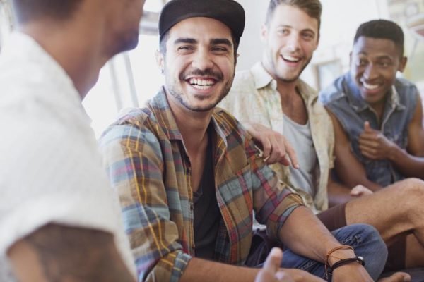 Foto colorida de quatro homens conbersando e sorrindo, um deles está de costas e os outros estõ de frente - Metrópoles