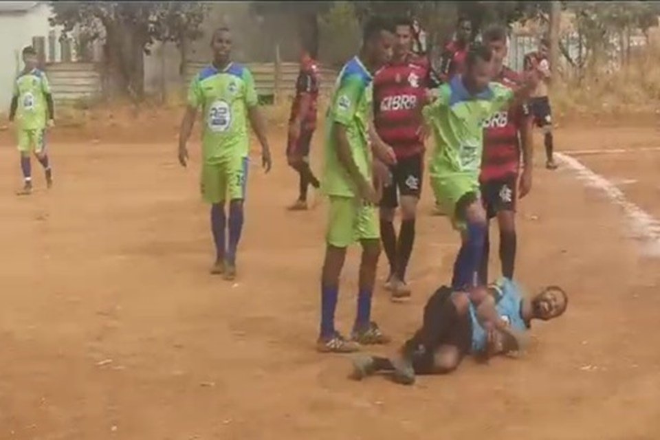 Imagem colorida mostra homem caído ao chão enquanto é agredido por outro