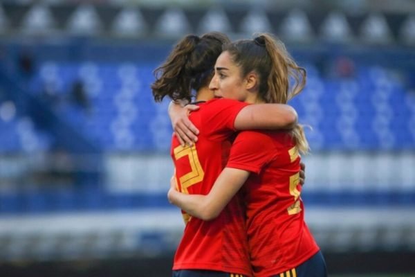 Imagem colorida da jogadora de futebol da Espanha, Olga Carmona, recebendo um abraço - Metrópoles