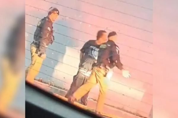 Fotografia colorida, policiais agredindo morardor de rua