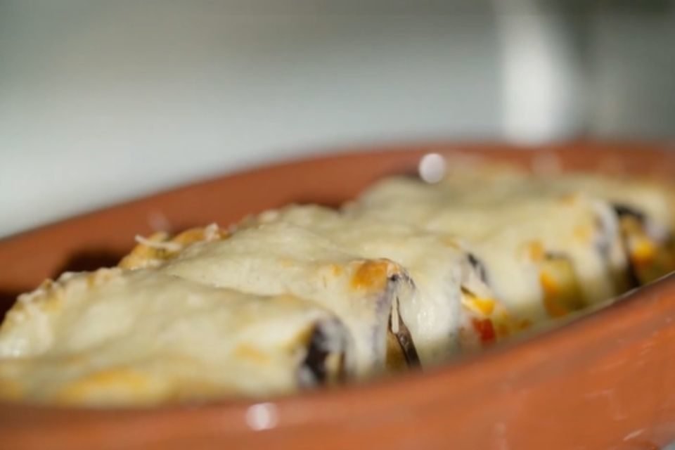 canelone de berinjela com queijo por cima em uma bandeja marrom - Metrópoles
