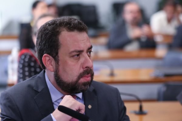 Boulos Imagem colorida mostra o deputado Guilherme Boulos em um dos auditórios da Câmara. Homem branco, de cabelo e barba castanhos, ele veste terno cinza - Metrópoles