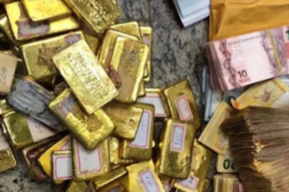foto colorida de barras de ouro ao de cédular de dinheiro - Metrópoles