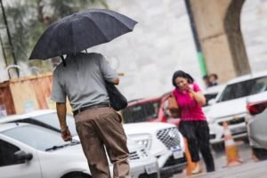 homem com guarda-chuva caminha perto de carros