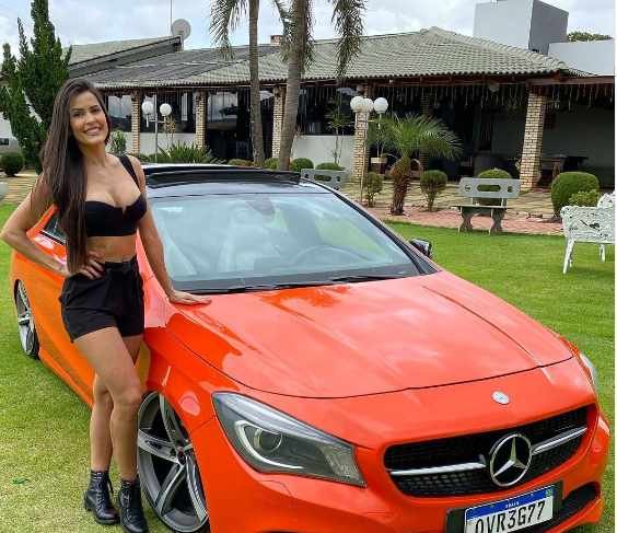 mulher morena ao lado de carro vermelho