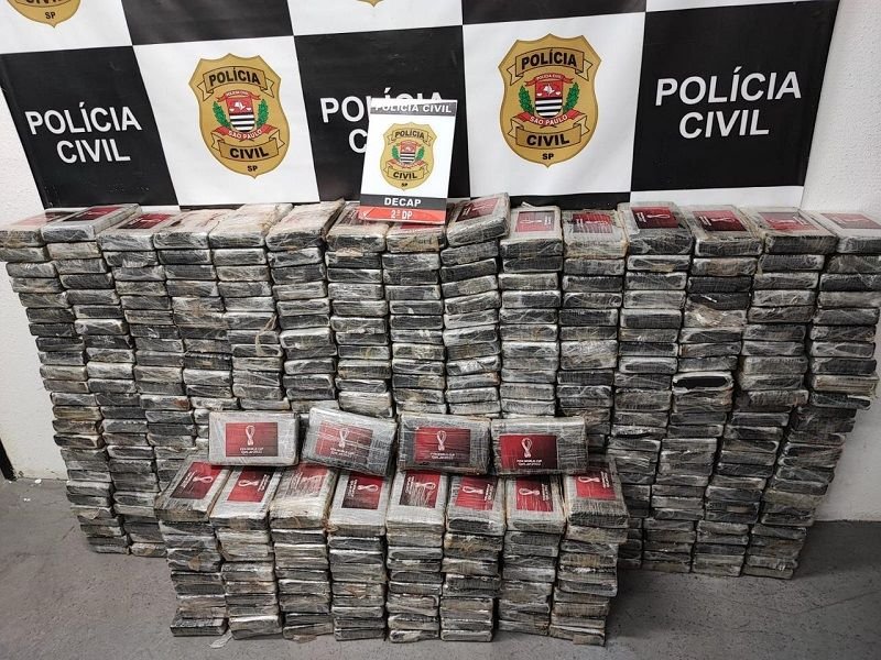 Imagem colorida mostra pacotes de cocaína empilhados na frente de uma parede com o logo da Polícia Civil de São Paulo - Metrópoles