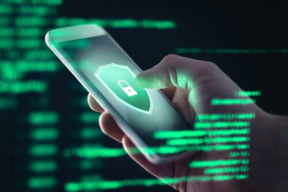 Uma mão mexendo no celular, que tem uma imagem de cadeado na tela - Metrópoles