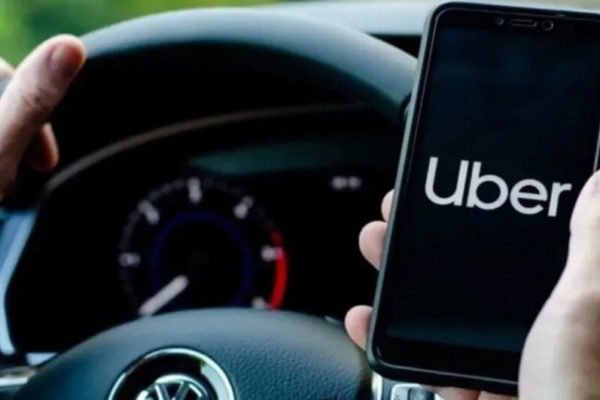 Imagem colorida de mão segurando um celular no aplicativo da Uber - Metrópoles
