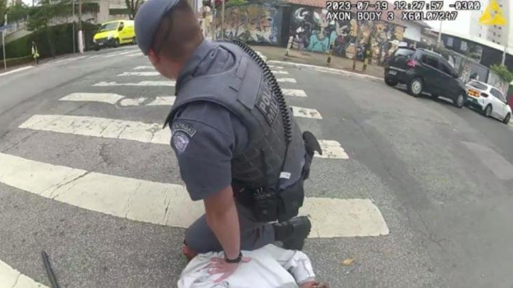 Imagem colorida mostra policial militar com o joelho em cima de um homem vestido com uma camiseta branca. Após ver as imagens, desembargadora mandou soltar o homem - Metrópoles