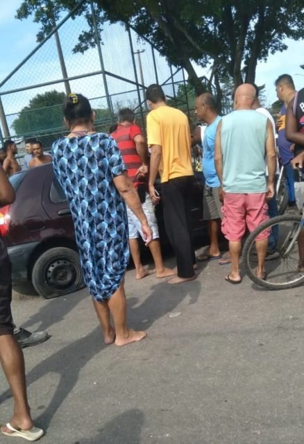 Imagem colorida de populares em torno do carro com mulheres baleadas por milicianos no RJ - Metrópoles