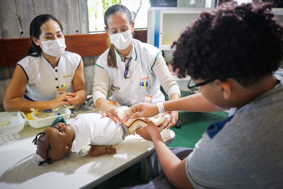 Foto de equipe médica mostrando boneca para menino - Metrópoles