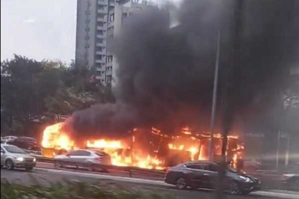 Imagem colorida de ônibus coberto pelo fogo e com fumaça preta acima em via movimenta de São Paulo - Metrópoles