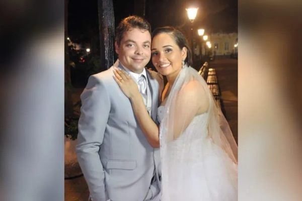 Na foto, um homem e uma mulher vestido de noivos posam para a câmera sorrindo - Metrópoles