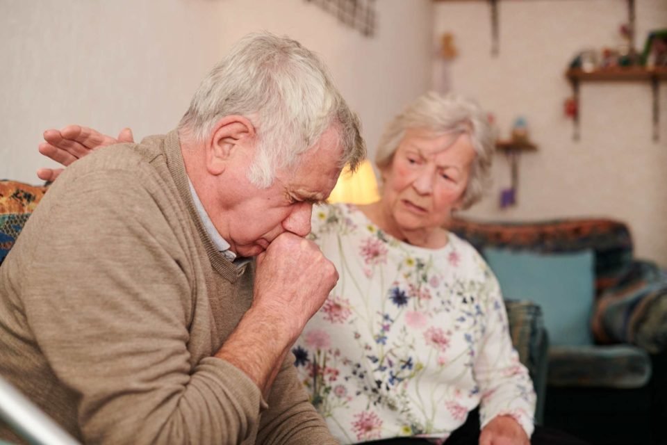 Foto mostra casal de idosos, um deles tossindo