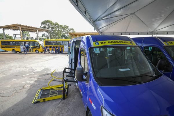 Pátio com os 40 novos ônibus escolares e em destaque uma van azul que é para garantir o transporte acessível