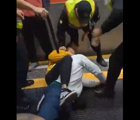 Imagem colorida de homem imobilizando outro no chão de estação de trem; seguranças estão ao redor - Metrópoles