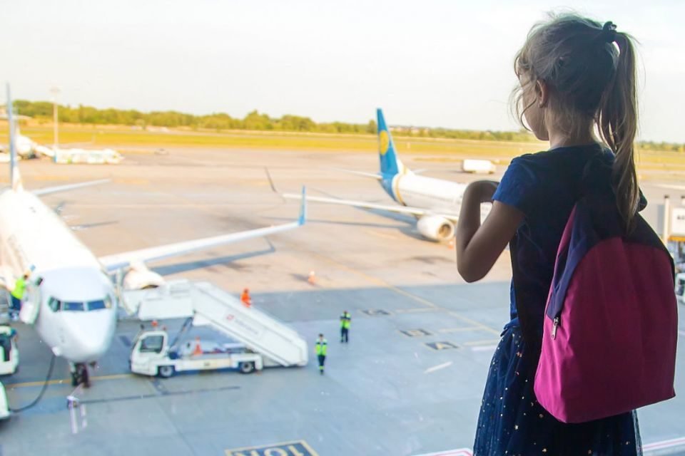 Menina em Aeroporto olhando para aviões - Metrópoles