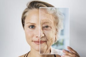 Foto colorida de mulher com parte do rosto coberto por foto com pele envelhecida - Metrópoles