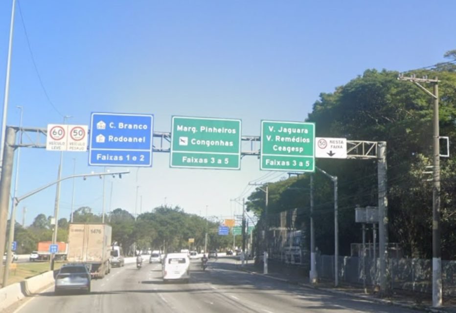 Imagem mostra placas de trânsito, radar e tráfego em avenida - Metrópoles