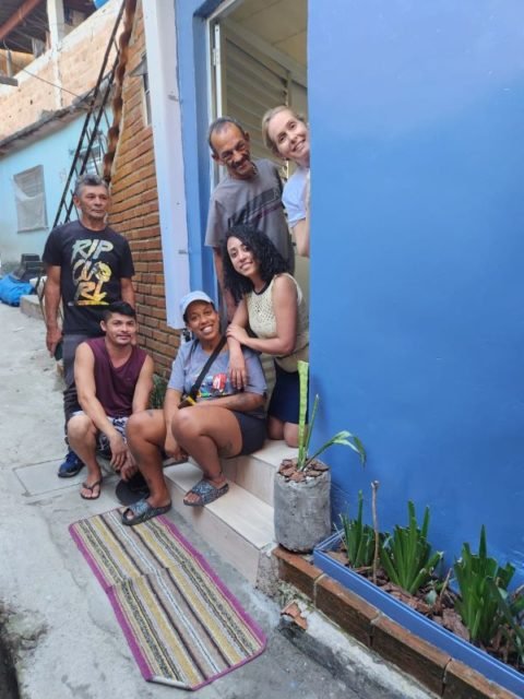 imagem colorida mostra 6 pessoas em frente à casa com parede azul - metrópoles