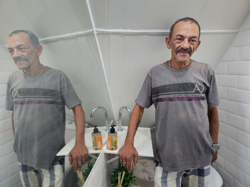 imagem colorida mostra homem negro de camiseta cinza em banheiro - metrópoles