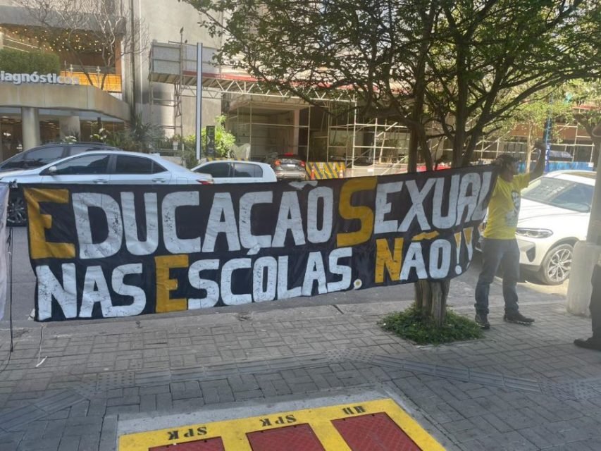 Imagem colorida mostra uma faixa na qual está escrito: 