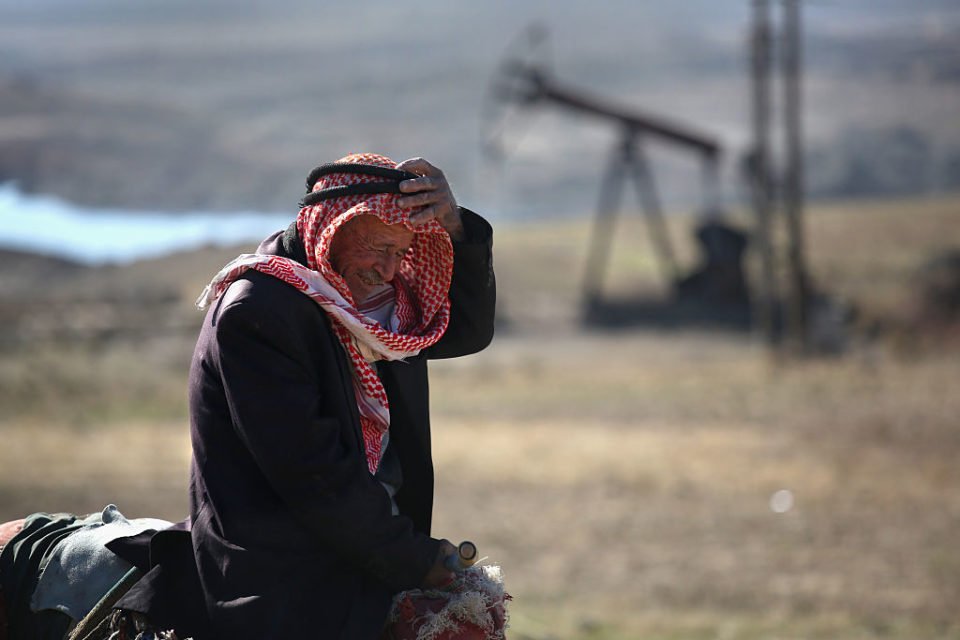 Foto colorida de um sírio chorando próximo a um campo de petróleo na Síria - Metrópoles