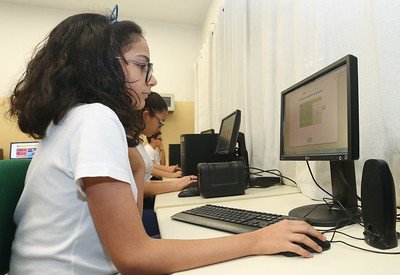 imagem colorida mostra criança utilizando computador em escola - metrópoles