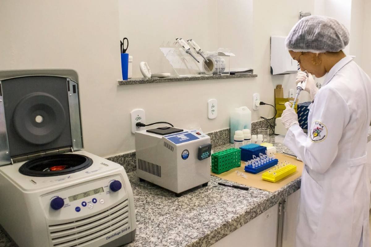 Fotografia colorida mostrando cientista fazendo testes com frascos em equipamentos-Metrópoles