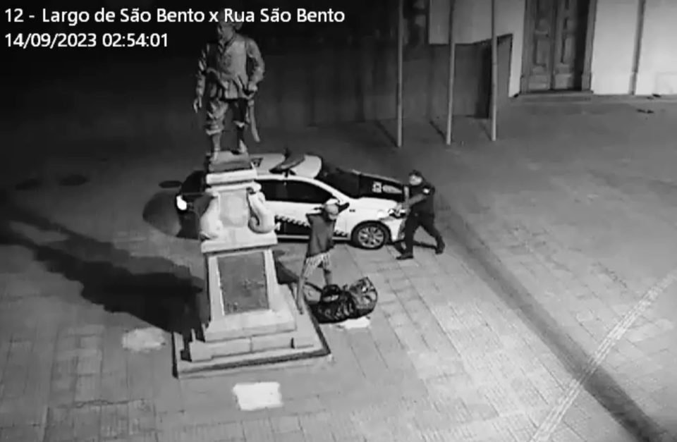 Imagem em preto e branco mostra policial apontando uma arma a um homem suspeito de tentar roubar uma estátua em Sorocaba, interior de São Paulo - Metrópoles