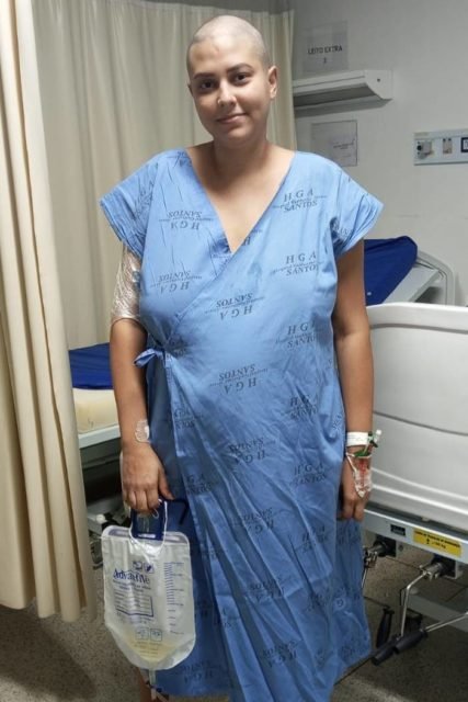 Foto de mulher com avental de hospital segurando bolsa de colostomia durante tratamento contra câncer - Metrópoles