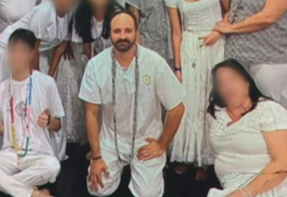 foto colorida mostra imagem de pai de santo vestido de branco, com um longo colar no pescoço; ele é calvo e tem barba e bigode; outras pessoas de branco no entorno - Metrópoles