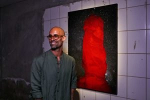 Fotografia colorida de Bruno Stuckert ao lado de uma obra da exposição Desatar